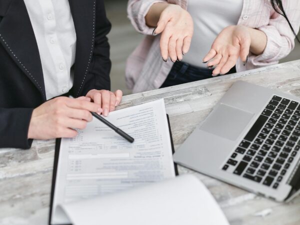 Two individuals reviewing Insurance policy at desk with laptop