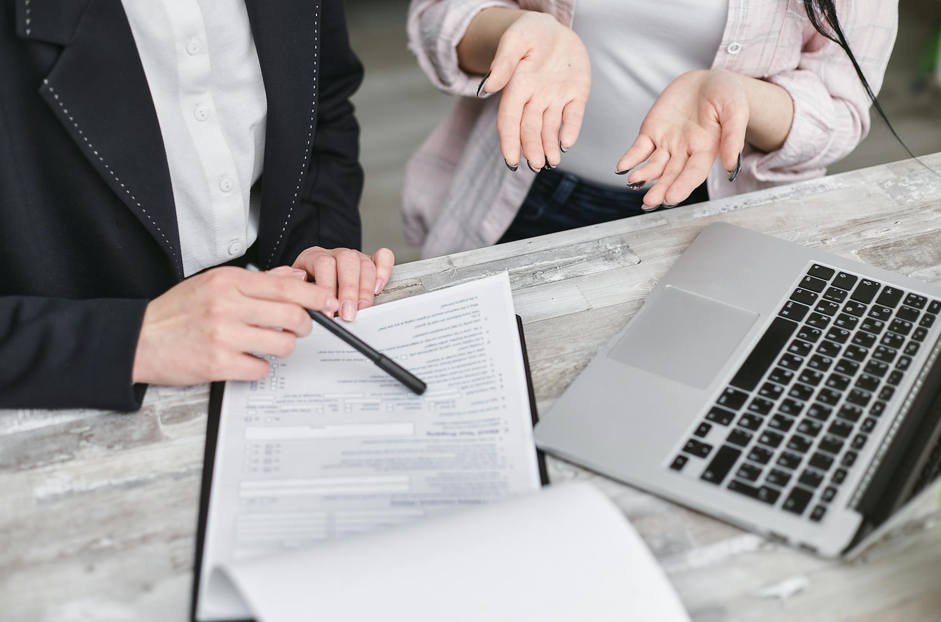 Two individuals reviewing Insurance policy at desk with laptop